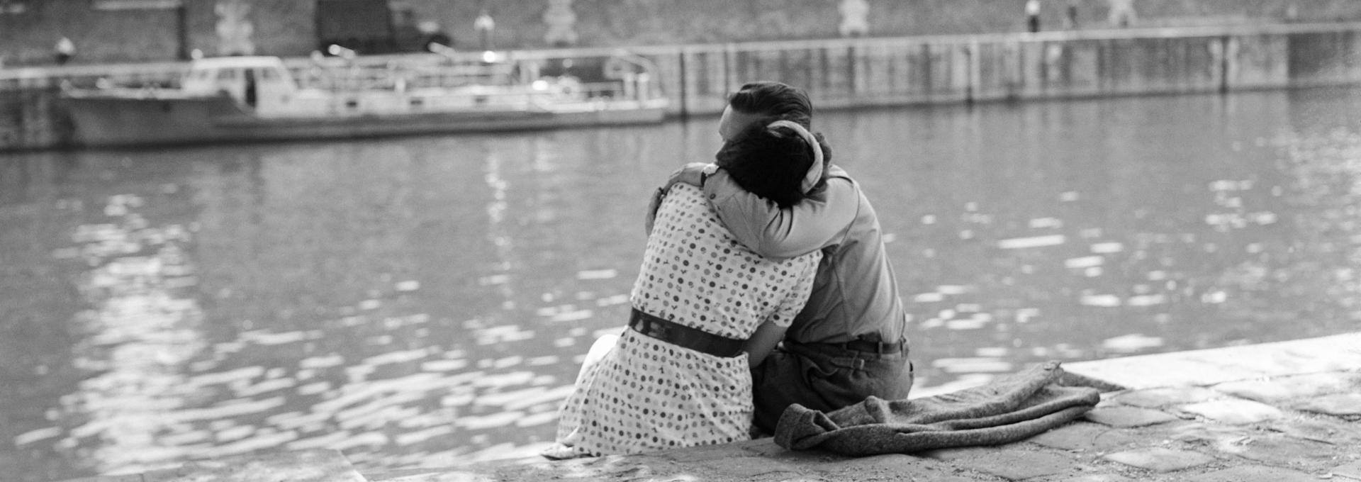 A loving couple embraces on the banks of the Seine river on June 5, 1950