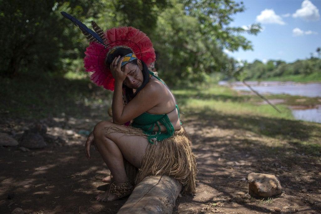 An indigenous woman from the Pataxo Ha-ha-hae community cries while looking at the Paraopeba river covered in mud, on the sixth day after the collapse of a dam at an iron-ore mine near the town of Brumadinho. Mauro Pimentel/AFP