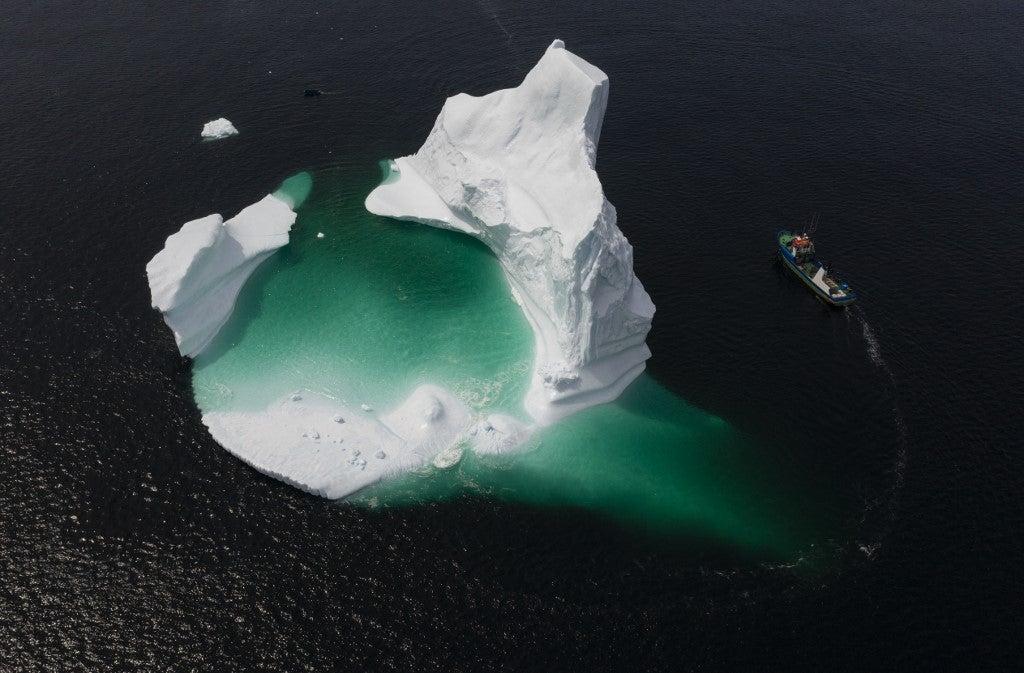 This aerial photo shows the boat of Captain Edward Kean passing an iceberg in Bonavista Bay on June 29, 2019 in Newfoundland, Canada. Johannes Eisele/AFP