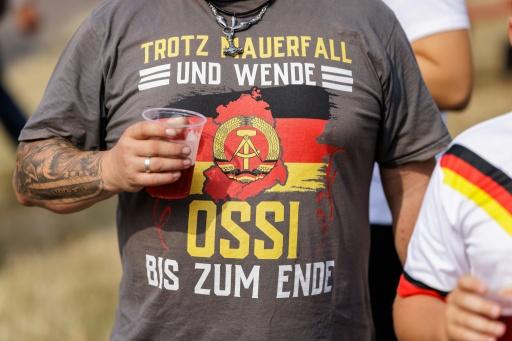 Un hombre en un mitin de la AfD lleva una camiseta con el emblema del martillo y el compás de Alemania Oriental y el lema "A pesar de la caída del Muro y la reunificación, un Ossi hasta el final" — Jens SCHLÜTER / AFP
