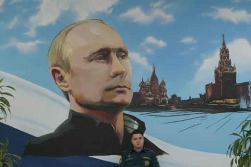Un panneau mural représentant Vladimir Poutine et la Place rouge, le 20 septembre 2026 dans un bureau de vote de Donetsk, dans les territoires ukrainiens occupés par la Russie — STRINGER / AFP