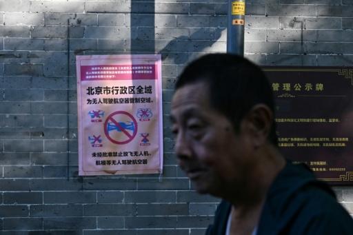 Un homme passe devant une affiche indiquant que l’ensemble de la zone administrative de Pékin constitue un espace aérien contrôlé pour les drones et autres aéronefs sans pilote, où tout vol est interdit sans autorisation, dans une ruelle de la capitale le 14 septembre 2026. — Pedro PARDO / AFP