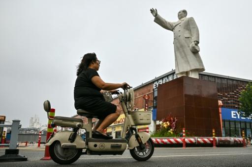 A woman riding her scooter past the late Communist leader Mao Zedong's statue in Shijiazhuang, in northern China's Hebei province — Pedro PARDO / AFP