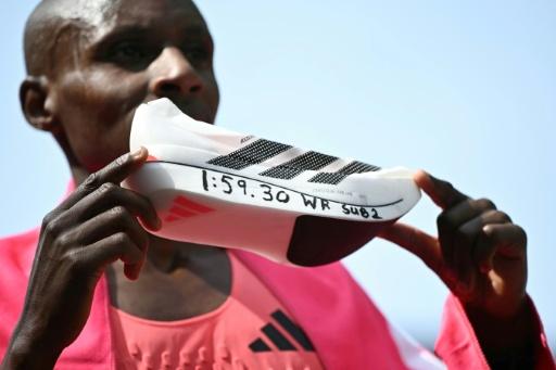 Kenya's Sabastian Sawe holds a shoe with his world record time written on the side. — JUSTIN TALLIS / AFP