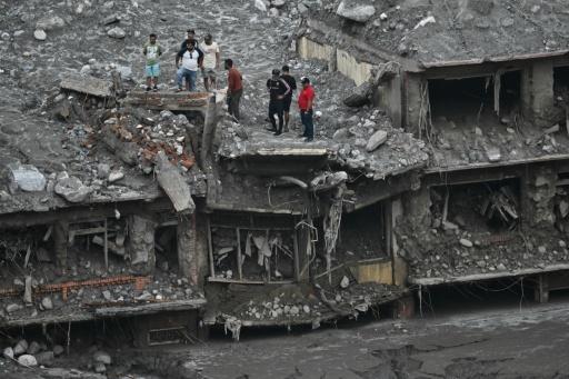 Des habitants sur le toit de maisons endommagées et couvertes de boue au lendemain de crues soudaines à Trishuli, dans le