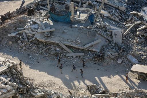 Children play football amid the ruins of destroyed buildings in Gaza City on July 27, 2026 — Omar AL-QATTAA / AFP