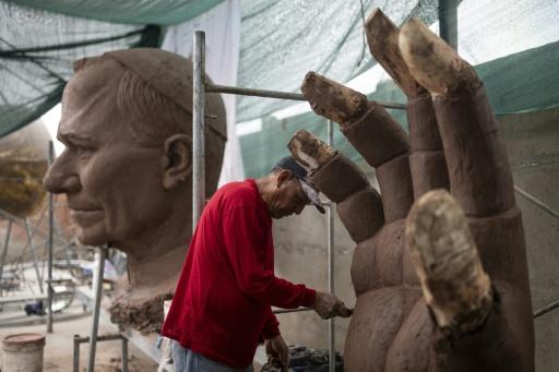 A craftsman adds clay to the fingers of the enormous hands of the sculpture — ERNESTO BENAVIDES / AFP