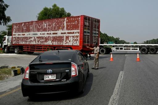 A police officer diverts traffic on the Islamabad–Peshawar Motorway blocked with trucks placed by authorities in Islamabad on September 24, 2026 ahead of opposition party Pakistan Tehreek-e-Insaf (PTI) protest demanding the release of former Prime Minister Imran Khan. — Aamir QURESHI / AFP