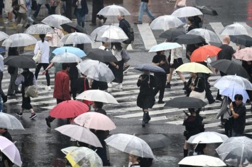 Pedestrians with umbrellas walk on a crossing as rain falls in Tokyo's Shibuya district — Rie KIKUCHI / AFP