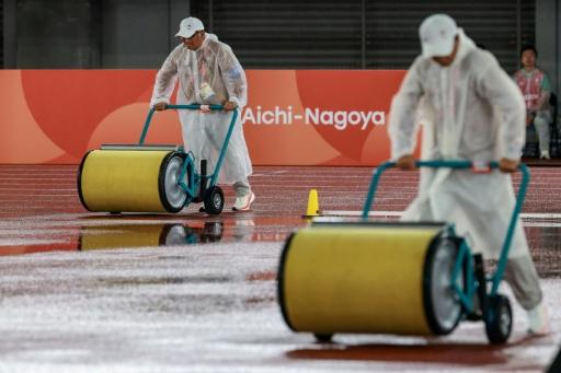 Officials dry the track as it rains on the athletics track on Monday — DAVID GRAY / AFP