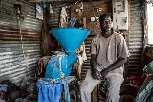 Amadou Gaye, 40 ans, est assis à côté d'une machine à moudre le millet dans sa boutique à Sukuta, en Gambie, le 12 septembre 2026 — MUHAMADOU BITTAYE / AFP