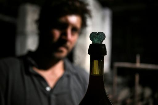Le directeur et copropriétaire du domaine viticole Château Coutet Adrien David-Beaulieu devant une bouteille retrouvée dans une cave du château datant du XVIIIe siècle, à Saint-Emilion, le 7 septembre 2026 — Christophe ARCHAMBAULT / AFP