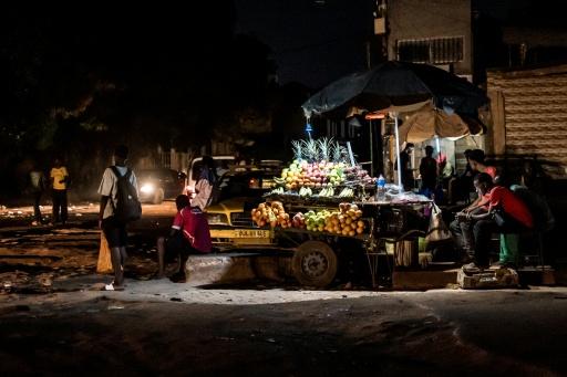 A fruit vendor is seen during a power outage in Westfield, The Gambia — MUHAMADOU BITTAYE / AFP