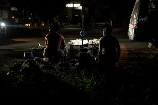 Vendors sell groundnuts on the side of the road during a power outage in Westfield, The Gambia — MUHAMADOU BITTAYE / AFP