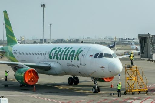 Des employés nettoient un Airbus A320 de la compagnie Citilink stationné sur le tarmac de l'aéroport Soekarno-Hatta, après la suspension des vols consécutive à l'éruption du volcan Anak Krakatau, le 7 septembre 2026 à Tangering, en Indonésie — SYARIEF Akbar / AFP