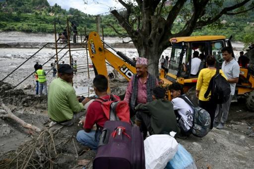 Des habitants regroupés près de la rivière Trishuli tandis que des ouvriers installent une tyrolienne au dessus du cours d'eau à Bidur au Népal le 2 septembre 2026 — Arun SANKAR / AFP