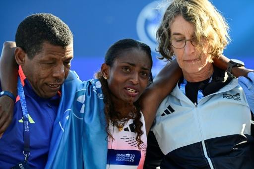 Ethiopia's Tigst Assefa (C) is helped off the track after winning the 2026 Berlin Marathon — John MACDOUGALL / AFP