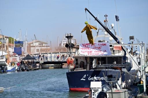 Une effigie suspendue à une grue, à côté d'une banderole, sur un bateau au port du Grau-du-Roi, lors d'une manifestation de pêcheurs contre la flambée des prix du carburant, le 17 septembre 2026 dans le Gard — Sylvain THOMAS / AFP