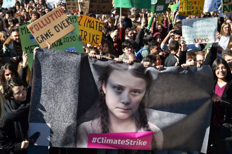 Pessoas e estudantes seguram cartazes e uma faixa mostrando a ativista política sueca Greta Thunberg, de 16 anos, em protesto contra o aquecimento global no centro de Roma, em 15 de março de 2019. Andreas SOLARO / AFP