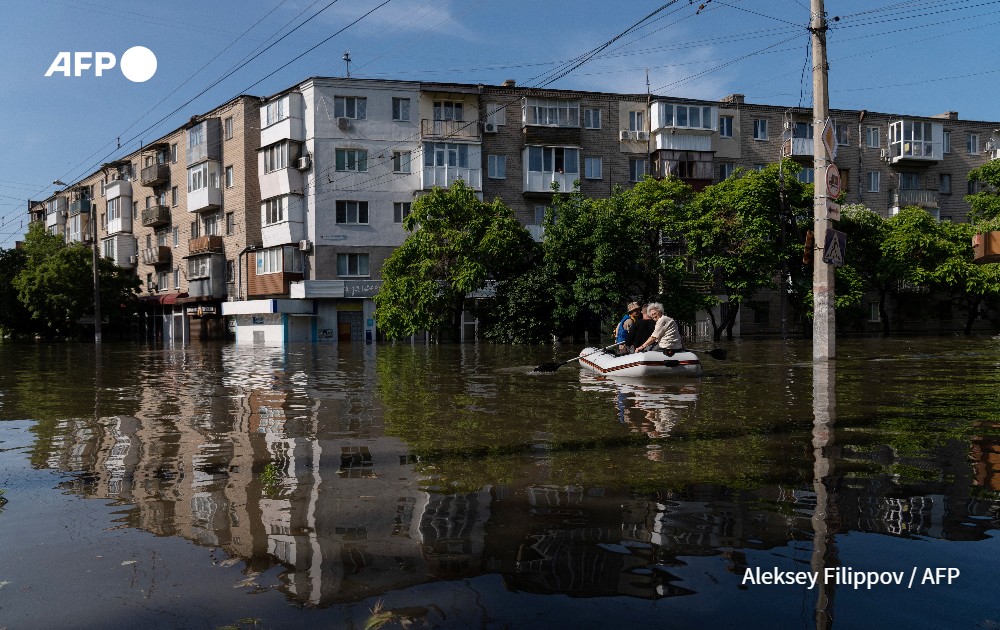 Ukrainian security forces transport local residents in a boat during an evacuation from a flooded area in Kherson